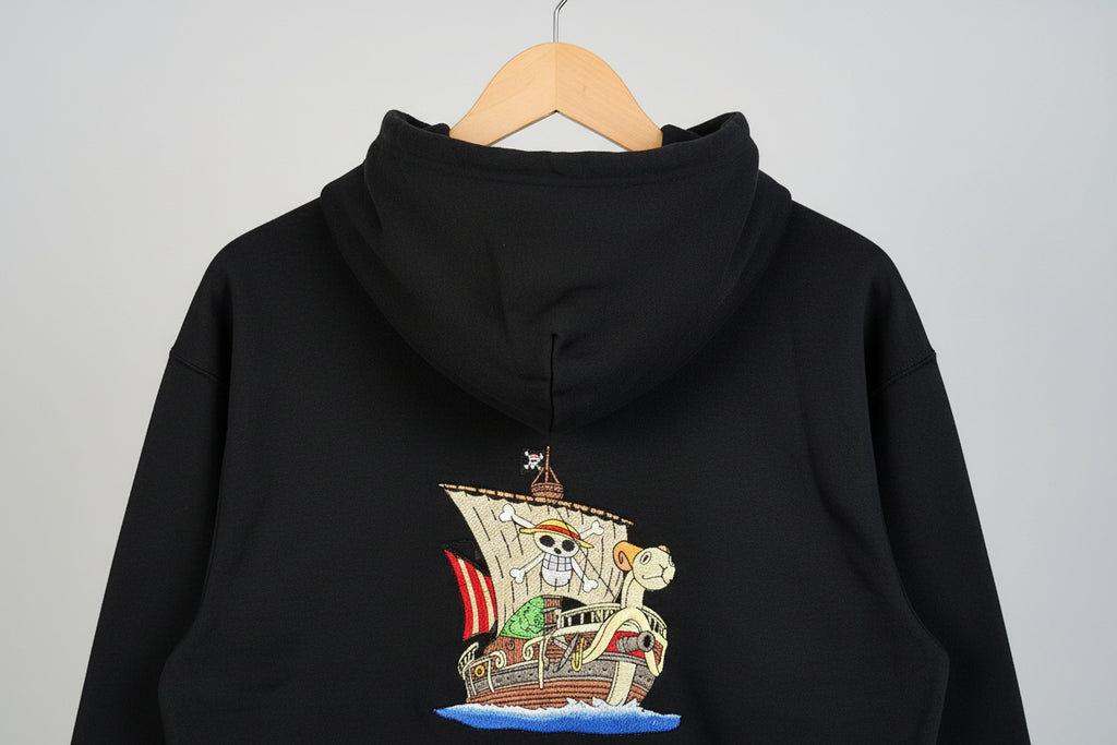 Black hoodie with a pirate ship design on the back against a neutral background
