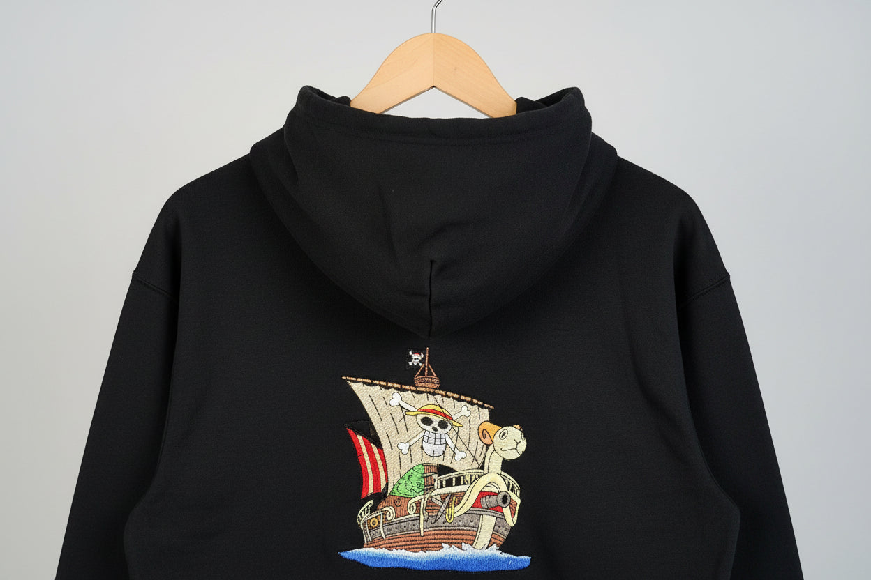 Black hoodie with a pirate ship design on the back against a neutral background